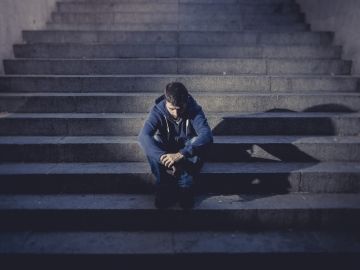 A man sits on a dimly lit staircase.