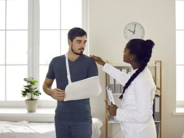 A doctor with a patient who has his arm in a sling.