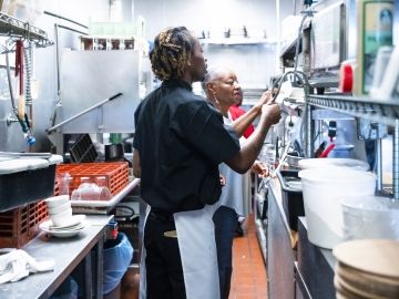 Two workers in a restaurant kitchen.