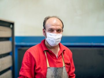 A worker wearing an apron and a cloth facial mask 