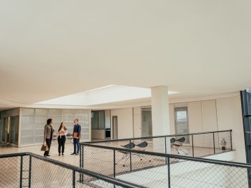 Three people in business attire talk in a hallway