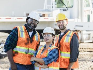 Three construction workers smile for the camera