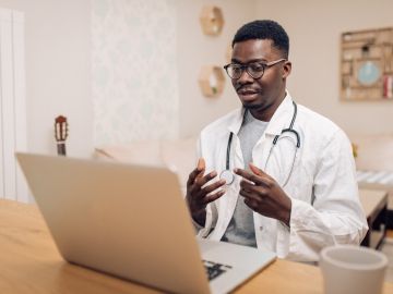 A young male doctor engaging in an online discussion using his laptop
