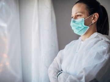 A health-care worker wearing a face mask and body covering