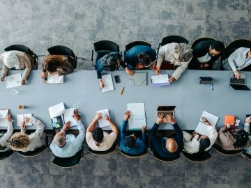 An overhead shot of a boardroom table full of people
