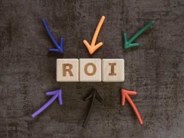 Wooden block letters spelling out R O I, with colourful arrows pointing to them