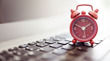 An alarm clock sits on a computer keyboard.