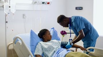 A nurse takes his patient's blood pressure.