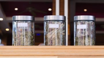Jars of cannabis on a store display, as seen from outside