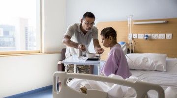 A man feeds his mom at a hospital bedside