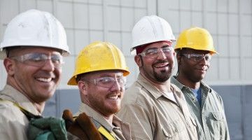 Four construction workers smile at camera