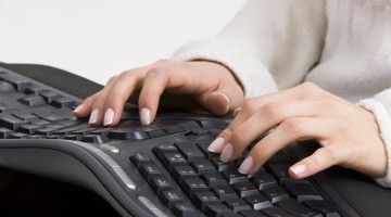A close-up view of a pair of hands using an ergonomic keyboard