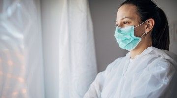 A health-care worker wearing a face mask and body covering