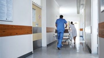 Hospital workers push bed down hallway