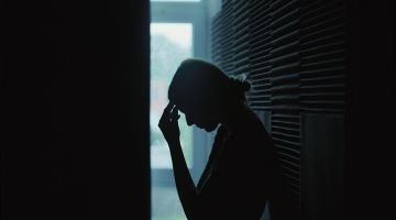 A silhouette of a women holding her head in her hand