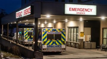 Two ambulance parked at the emergency entrance of a hospital in the night