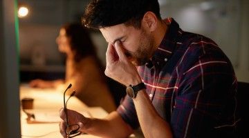 A worker rubs his eyes as he works late