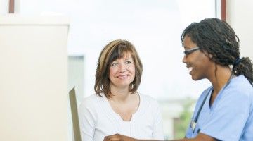 A smiling doctor consults with a patient at her desk