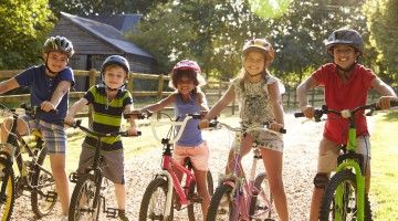 Five kids on bikes wearing bike helmets