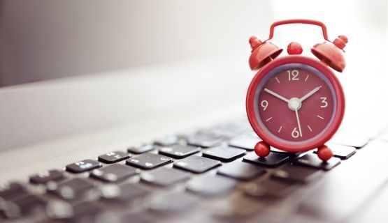 An alarm clock sits on a computer keyboard.