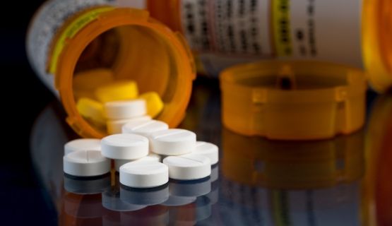 A bottle of pills spilled on a table.