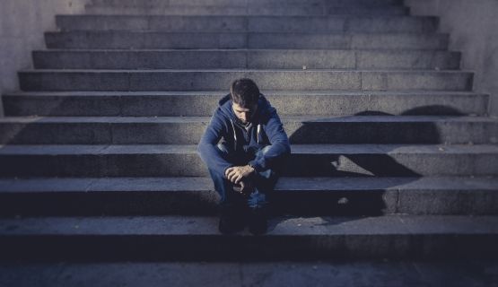 A man sits on a dimly lit staircase.