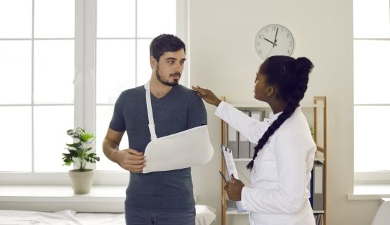 A doctor with a patient who has his arm in a sling.