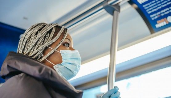 A masked worker riding a bus