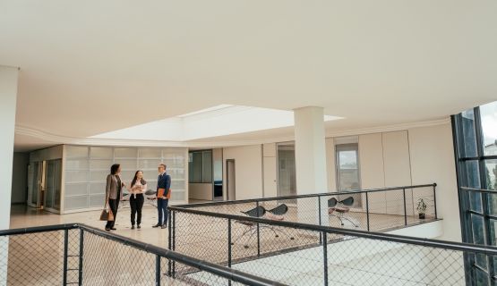 Three people in business attire talk in a hallway