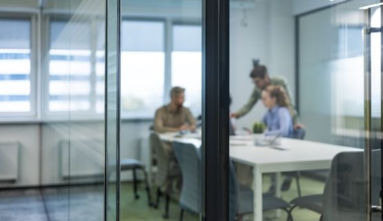 Business professionals in casual wear, sit around a table in a boardroom, with blurred background