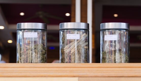 Jars of cannabis on a store display, as seen from outside