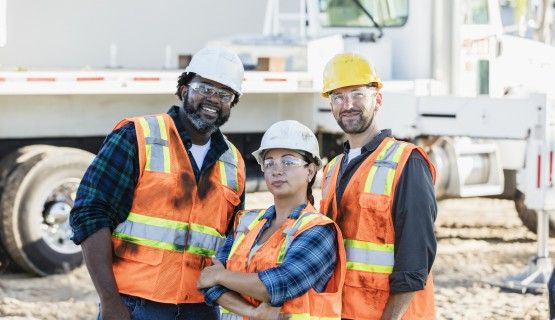 Three construction workers smile for the camera