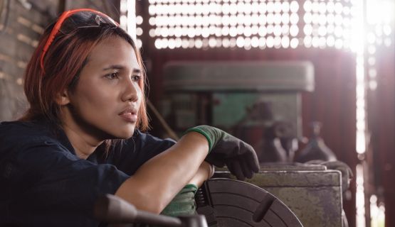 female factory worker sitting on floor with tools, looking worried about what to do