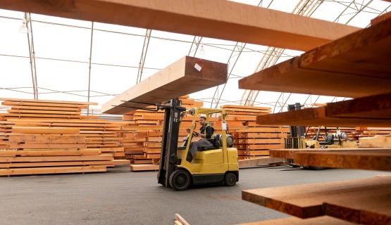 A worker drives a forklift in a lumber mill