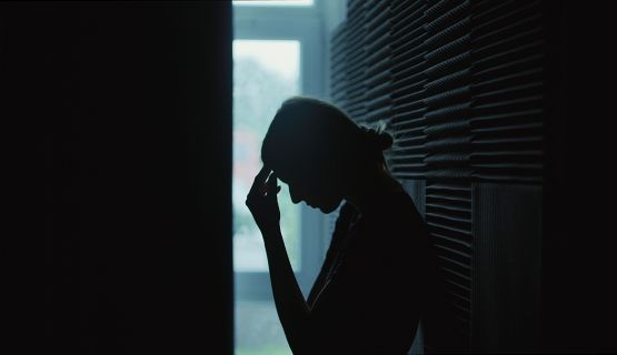 A silhouette of a women holding her head in her hand