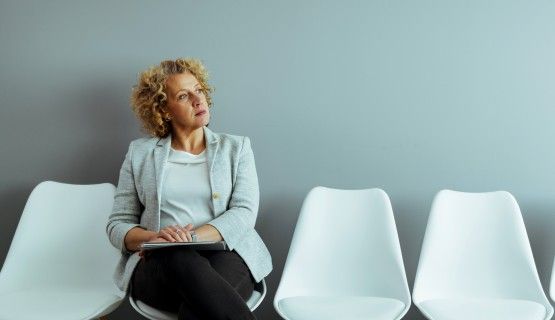 An older female worker ponders decision while sitting in waiting room