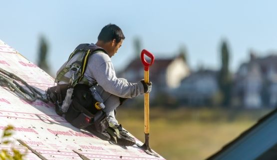 A worker sits on top of the roof of a residential new build
