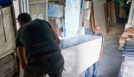 Two men lift heavy furniture off a truck