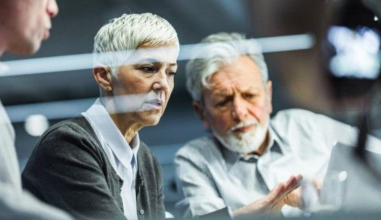 Two grey-haired workers have a discussion