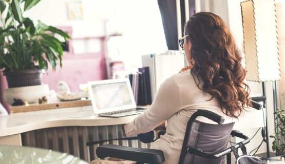 A woman in a wheelchair works from her home office