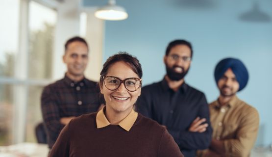 Workers of various ethnicities pose happily with their work team