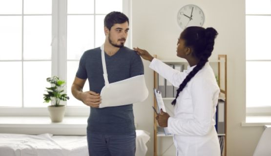 A doctor with a patient who has his arm in a sling.