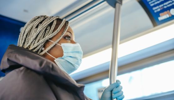 A masked worker riding a bus