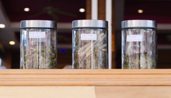 Jars of cannabis on a store display, as seen from outside