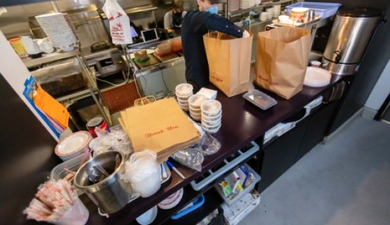 Masked restaurant worker prepares take-out food orders