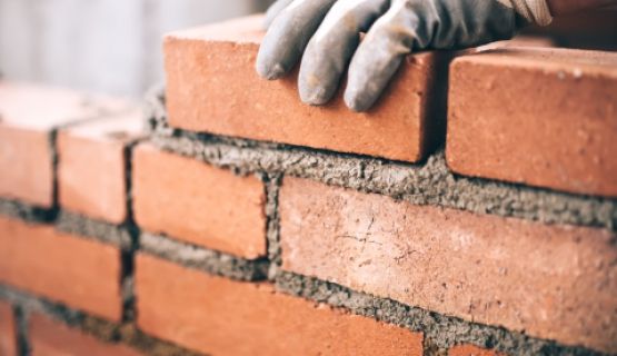 Gloved hand laying bricks Thumbnail