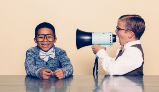 Boy shouting through megaphone to another boy Thumbnail