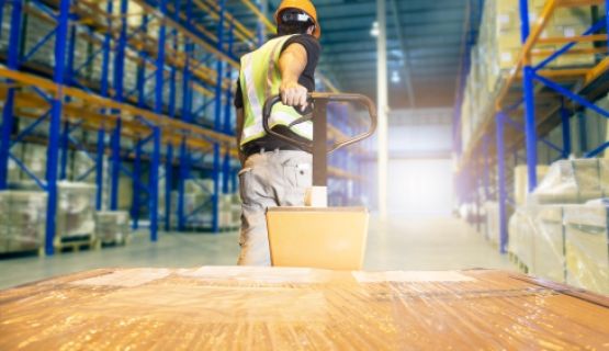 The back of a male worker, hauling a load in a warehouse setting